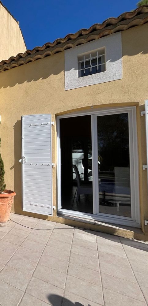 Volet battant blanc à côté d’une porte-fenêtre coulissante