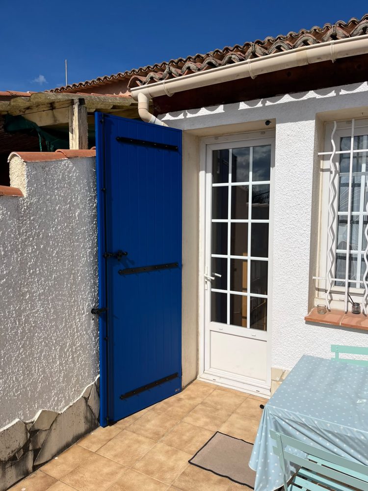 Volet battant bleu vif à côté d’une porte-fenêtre blanche