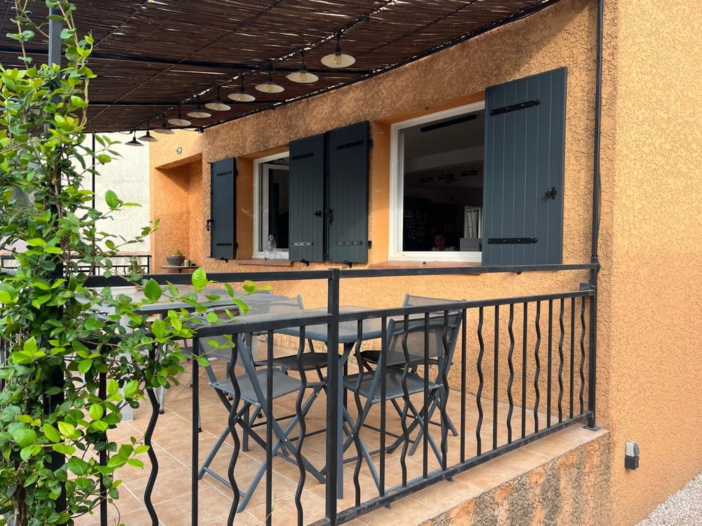 Terrasse avec volets battants gris anthracite sur une façade orangée